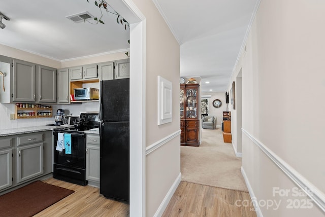 kitchen with crown molding, gray cabinets, visible vents, light wood-type flooring, and black appliances