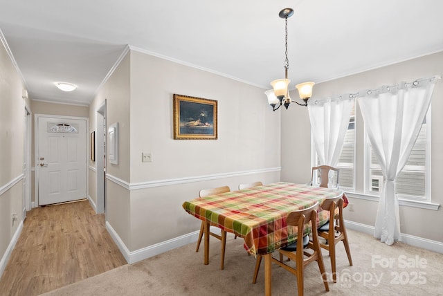 dining area featuring ornamental molding, light carpet, baseboards, and an inviting chandelier