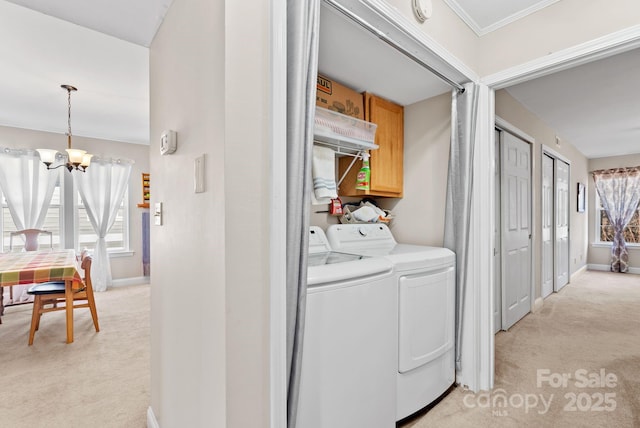 washroom with a notable chandelier, light carpet, separate washer and dryer, baseboards, and cabinet space