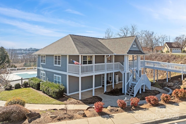 exterior space with a shingled roof, fence, stairway, and a patio