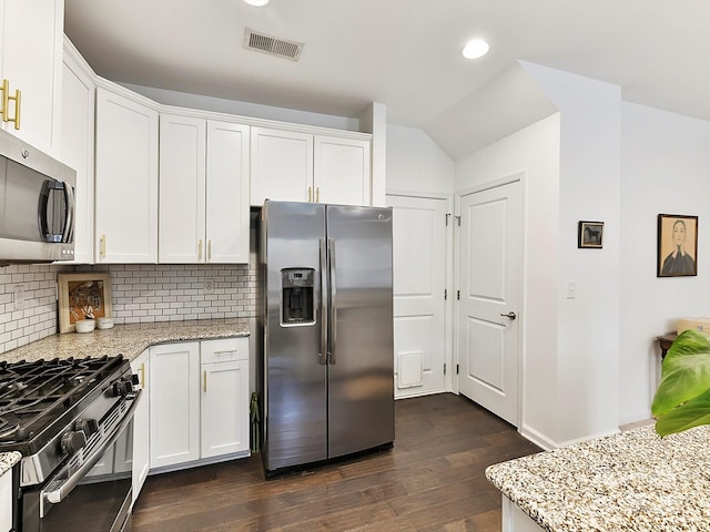 kitchen with dark wood-type flooring, backsplash, stainless steel appliances, light stone counters, and white cabinets