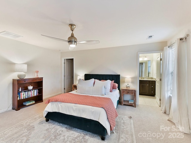 bedroom with ceiling fan, light colored carpet, and connected bathroom