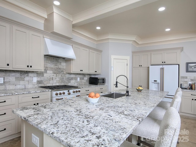 kitchen with premium range hood, sink, a kitchen island with sink, and high end appliances