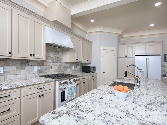 kitchen with high end appliances, sink, light stone countertops, and custom range hood