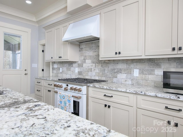 kitchen featuring ornamental molding, custom range hood, white cabinets, white range oven, and backsplash