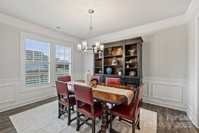 dining room with dark hardwood / wood-style flooring, crown molding, and a chandelier