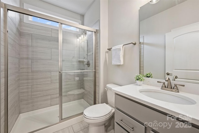 bathroom featuring vanity, a shower with shower door, and toilet