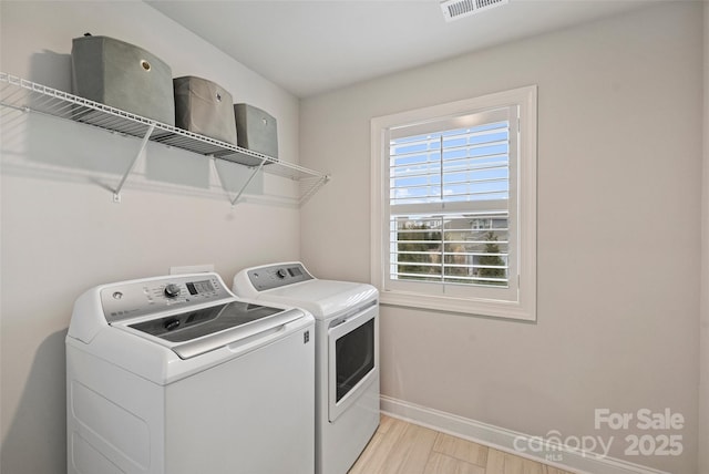 clothes washing area with independent washer and dryer and light hardwood / wood-style flooring