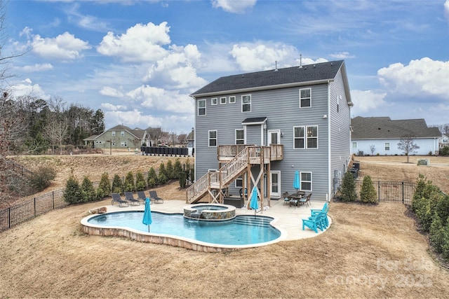 rear view of house with a swimming pool with hot tub, a patio, and a lawn