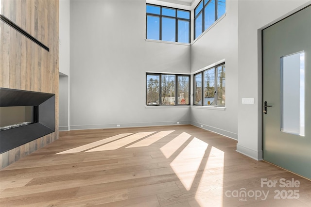 unfurnished living room with a high ceiling and light wood-type flooring