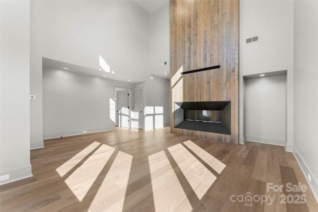 unfurnished living room with hardwood / wood-style flooring, a fireplace, and a high ceiling