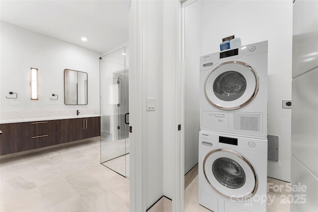 laundry area featuring stacked washer / drying machine and sink