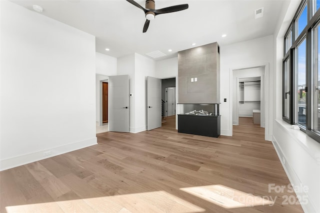 interior space with a towering ceiling, light hardwood / wood-style flooring, and ceiling fan