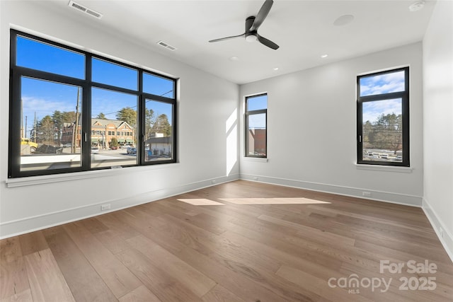 empty room featuring plenty of natural light, hardwood / wood-style floors, and ceiling fan