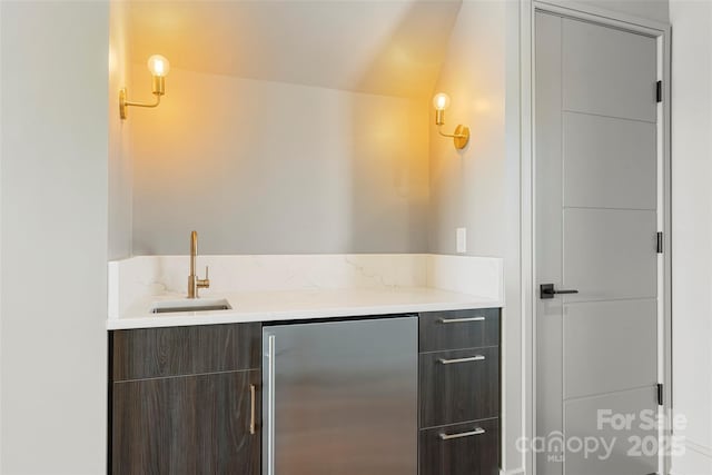 bar featuring vanity, vaulted ceiling, and stainless steel refrigerator