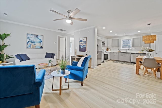 living room with crown molding, ceiling fan, sink, and light hardwood / wood-style flooring