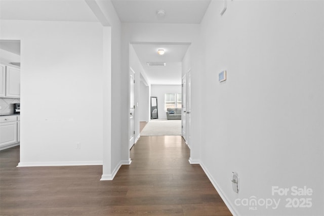 hallway featuring dark wood-style floors and baseboards