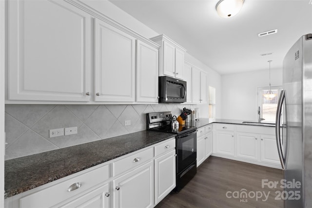 kitchen with black / electric stove, a sink, white cabinetry, freestanding refrigerator, and dark stone countertops