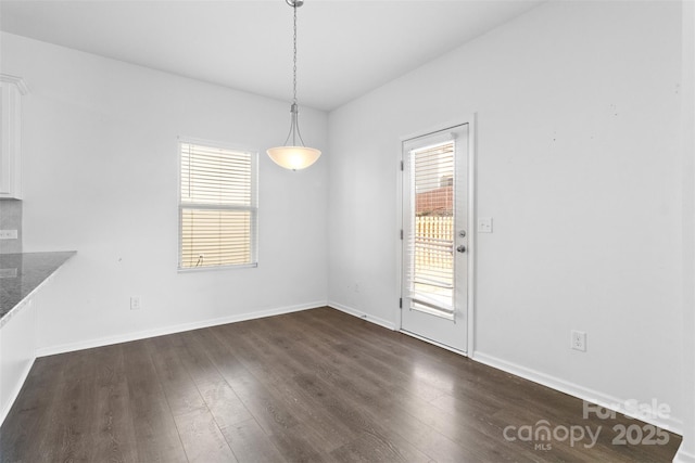 unfurnished dining area with a wealth of natural light, dark wood finished floors, and baseboards