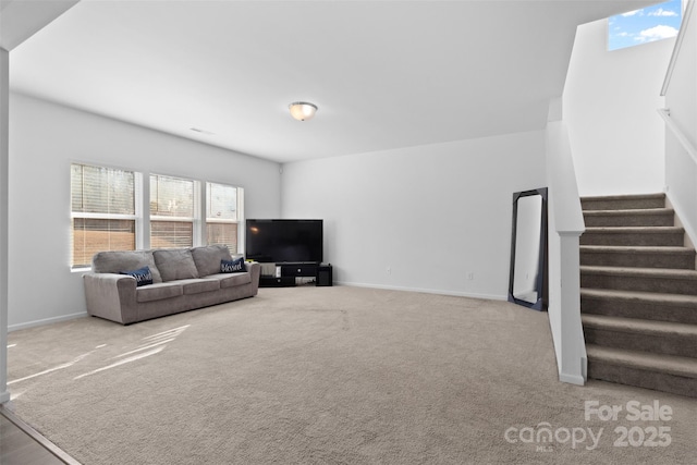 carpeted living area featuring stairway and baseboards