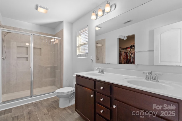 full bath featuring wood finished floors, a sink, visible vents, and a shower stall