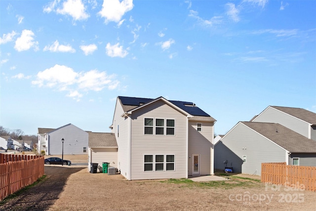 rear view of house featuring central AC, fence, and a residential view