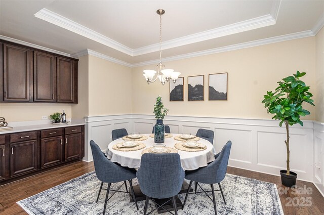 dining space with a chandelier, a decorative wall, dark wood-style flooring, and a wainscoted wall