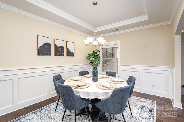 dining room featuring a decorative wall, a notable chandelier, dark wood-style flooring, visible vents, and crown molding