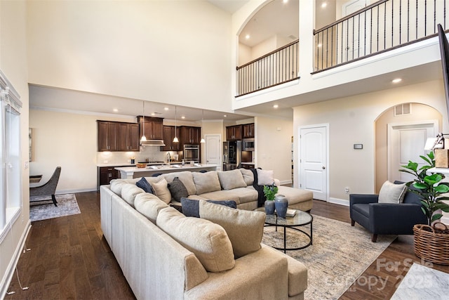 living area featuring recessed lighting, visible vents, a towering ceiling, dark wood-type flooring, and baseboards