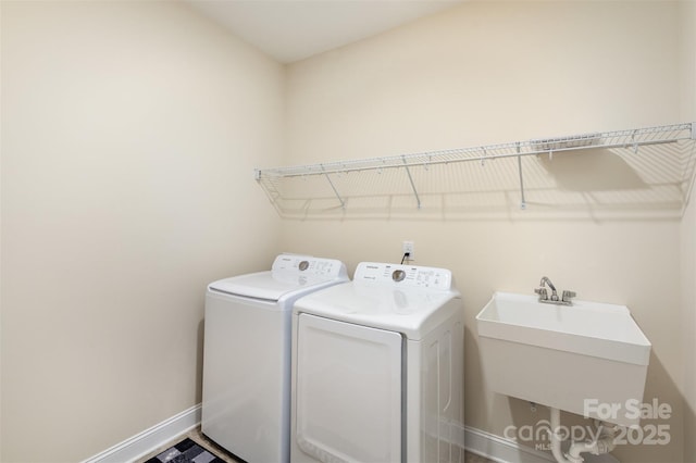 laundry area featuring laundry area, washer and clothes dryer, a sink, and baseboards