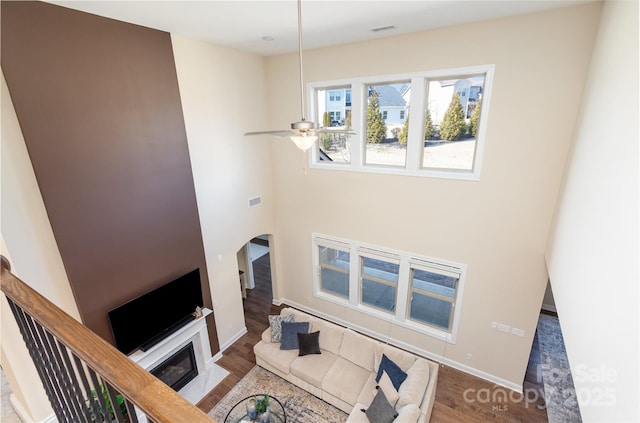 living area with visible vents, arched walkways, a ceiling fan, and wood finished floors