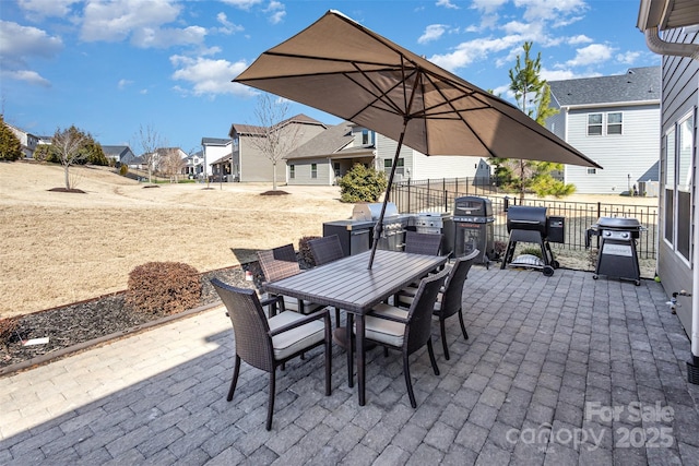 view of patio featuring a grill, a residential view, fence, and outdoor dining area