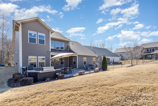 rear view of house with a patio area, a shingled roof, fence, and a yard