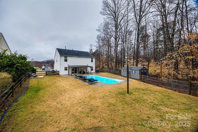 rear view of property with a storage shed, a yard, a fenced in pool, and a patio