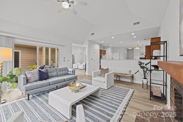 living room featuring ceiling fan, high vaulted ceiling, and light hardwood / wood-style floors