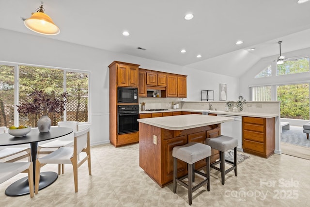 kitchen with vaulted ceiling, a kitchen breakfast bar, kitchen peninsula, pendant lighting, and black appliances