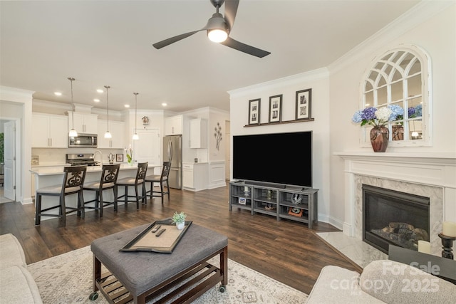 living area with ornamental molding, dark wood-type flooring, a high end fireplace, and recessed lighting