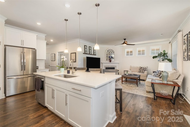 kitchen with white cabinets, appliances with stainless steel finishes, open floor plan, light countertops, and a sink