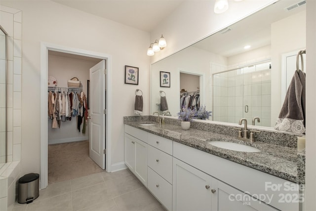 bathroom with a stall shower, a sink, visible vents, and tile patterned floors