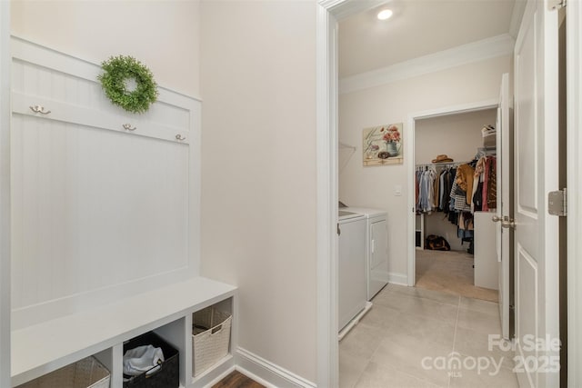 mudroom with ornamental molding, washer and dryer, baseboards, and light tile patterned floors