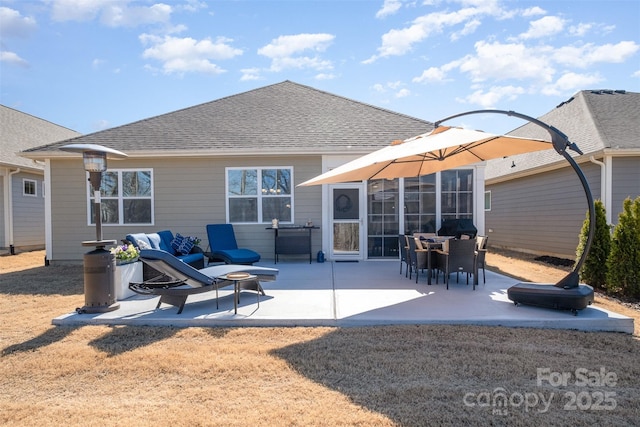 rear view of property featuring a shingled roof, a patio area, and a fire pit