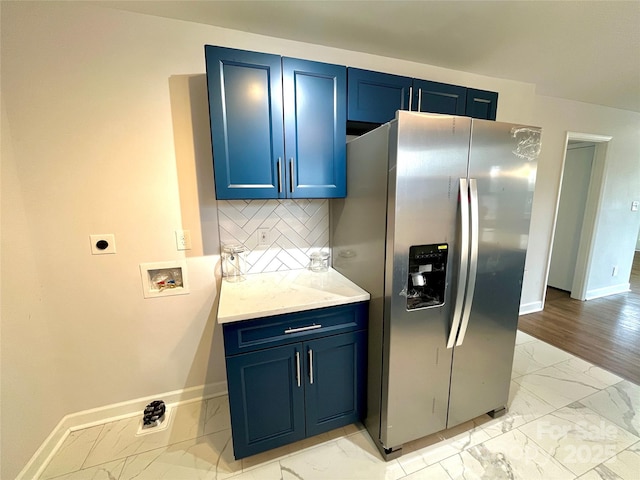 kitchen with blue cabinets, stainless steel fridge with ice dispenser, and decorative backsplash