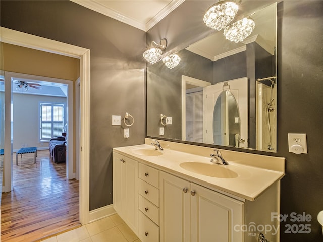 bathroom with tile patterned floors, ornamental molding, ceiling fan with notable chandelier, and vanity