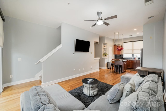 living room featuring light hardwood / wood-style flooring and ceiling fan