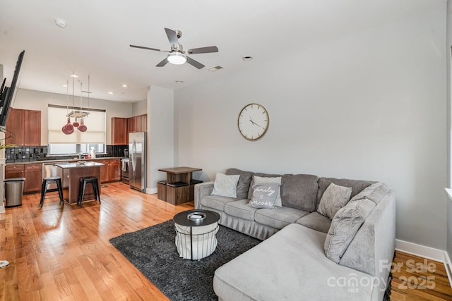 living room with ceiling fan and light hardwood / wood-style flooring