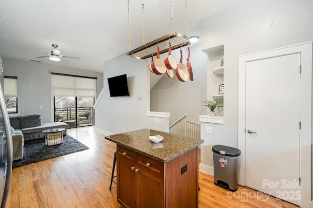 kitchen with stone counters, a kitchen island, radiator heating unit, and light hardwood / wood-style floors