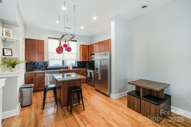 kitchen with appliances with stainless steel finishes, a kitchen island, a kitchen breakfast bar, and decorative backsplash