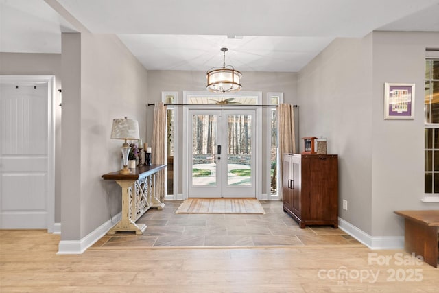 entryway with french doors, a chandelier, and light hardwood / wood-style flooring