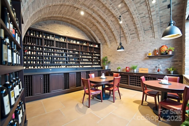 wine room featuring brick ceiling, vaulted ceiling, and brick wall