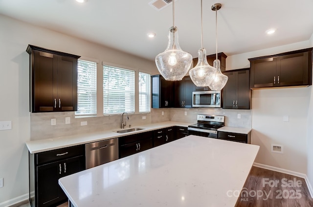 kitchen featuring sink, tasteful backsplash, decorative light fixtures, a center island, and stainless steel appliances